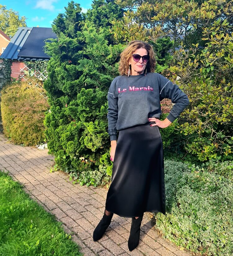 grey sweatherv on a silk midi skirt