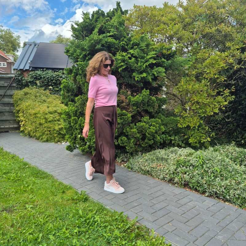 pink sneakers under a silk skirt