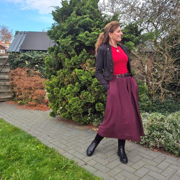 Aubergine skirt and red top with a black jacket and boots